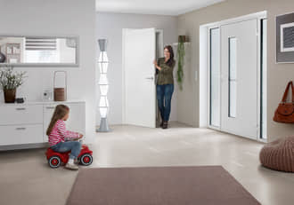 image of a mother observing her daughter riding a tricycle indoors